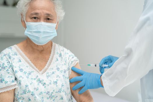 Elderly Asian senior woman wearing face mask getting covid-19 or coronavirus vaccine by doctor make injection.