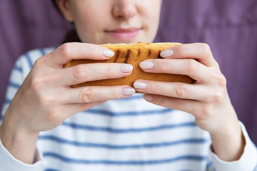 Portrait of a beautiful young woman who is enjoying food, fast food hot dog