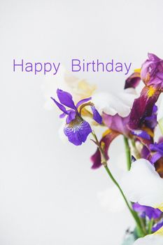 Crystal green vase full of faceted multi-colored hybrid bearded irises, vertical, happy birthday lettering