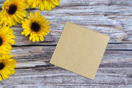 Torn brown paper on wooden surface and sunflower flat lay with copy space. Directly above.
