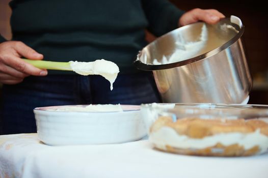 Close-up. Details of the hands of a female chef pastry preparing cheese cream for cake at home. Culinary, homemade dessert