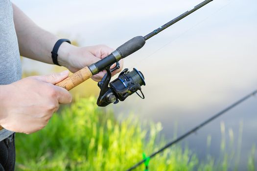 A fishing rod with a spinning reel in the hands of a fisherman. Fishing background. Outdoor recreation