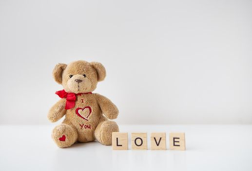 Valentine's day teddy bear and wooden letters with the inscription love. Place for an inscription