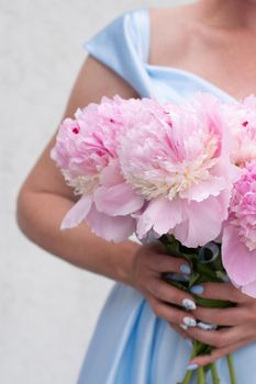 bride in a blue wedding dress with a bouquet of pink peonies, pastel paradise, floral background, complementary color combination. High quality photo