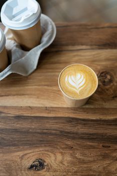 Cappuccino coffee with beautiful pattern on foam in eco craft glass on table favorite coffee cup concept. Coffee to go concept