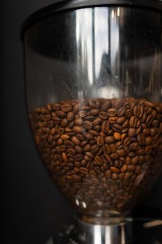 Coffee beans roasted and poured into a coffee grinder. The process of making coffee by a barista. Close-up