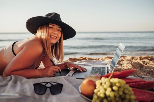 Close Up Side View of Cheerful Woman Dressed in Swimsuit Working on Digital Tablet and Laptop During Picnic by Sea