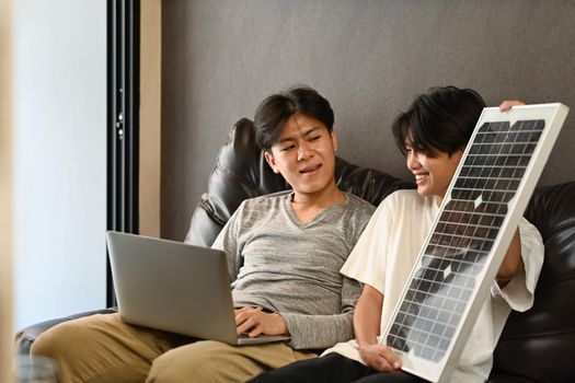 Young homosexual couple installing solar panels. Concept of Alternative renewable green energy, ecological renewable energy.