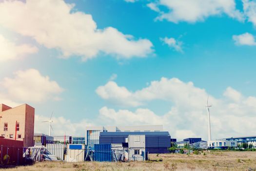 Wind turbine in the middle of industrial estate as a source of renewable energy on blue sky background