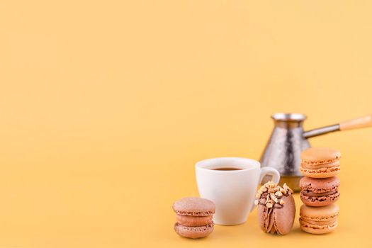 Close-up of Americano coffee, jezva, coffee pot and almond cookies on a yellow background