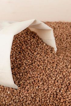 Buckwheat harvest. Poor agricultural harvests, food shortages, world hunger. A bag of buckwheat on a brown background with a white down arrow