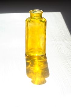 Empty glass yellow bottle with nice shadow against sun light