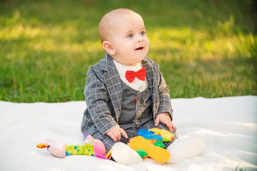 boy sitting on a white blanket with toys