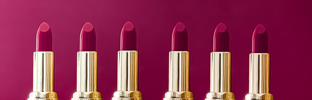 Purple lipsticks in golden tubes on colour background, luxury make-up and cosmetics for beauty brand product design concept