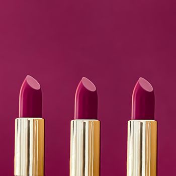Purple lipsticks in golden tubes on colour background, luxury make-up and cosmetics for beauty brand product design concept