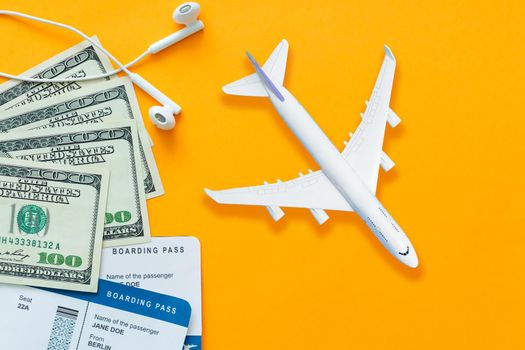Travel concept, air ticket, money, headphones over yellow background.