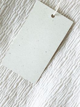 Blank fashion brand label tag, sale price card on luxury fabric background, shopping and retail concept