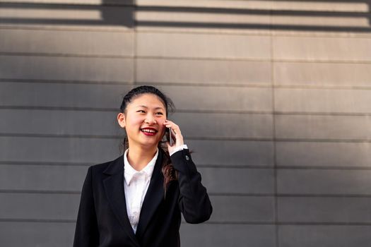 smiling asiatic businesswoman talking on the phone, concept of entrepreneurship and business, copy space for text