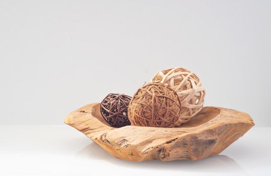 wicker balls from a vine of different natural colors on a wooden tray on a light background