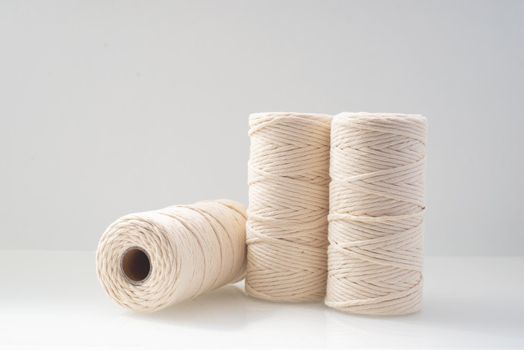 macrame threads wound bobbins of natural beige color are located on a light background