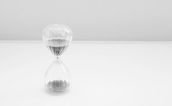 Hourglass, sandglass with sand on a white background with a streak of white light and a shadow