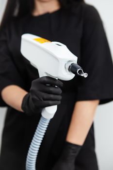 The master of laser hair removal holds a laser hair removal machine in his hands. Removal of hair on all parts of the body. Hair removal machine