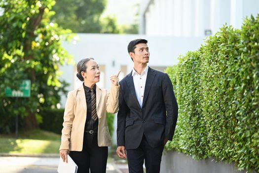 Two business people in formalwear discussing business while walking on street in modern city.