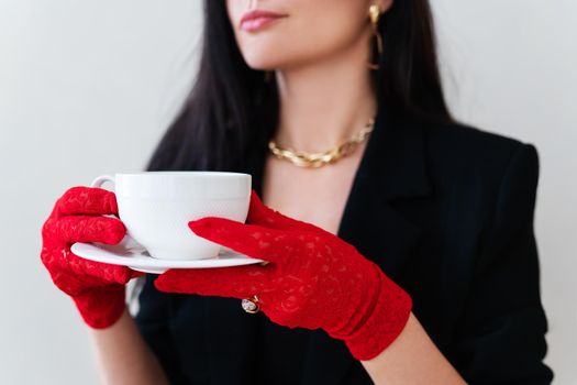 Vintage photo of a glamorous girl in vintage lace red gloves holding a white cup of coffee