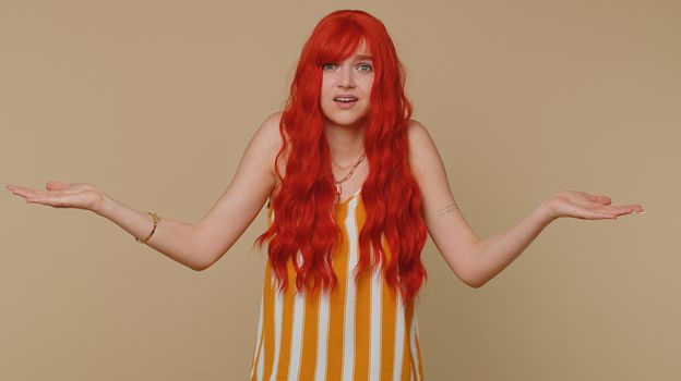 What Why. Sincere irritated redhead woman raising hands in indignant expression asking reason of failure demonstrating disbelief irritation by troubles. Confused girl isolated on beige wall background