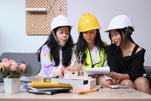 Three lovely asian girls in engineering uniform and safety helmet playing together at home.