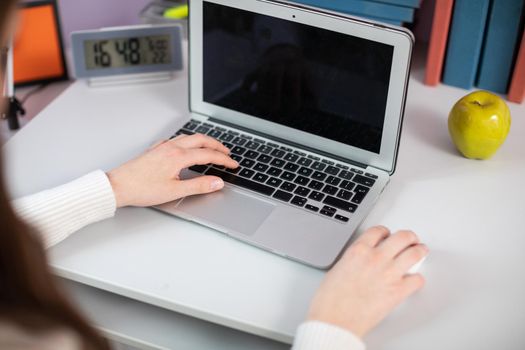 A teenager's left hand operates the laptop calvary and the right hand moves the mouse. Simultaneous keyboard and mouse operation by one person.