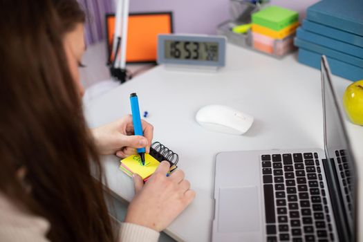 A student writes a word in English on a piece of paper with a blue marker. Individual foreign language learning at home. Visualize the words.