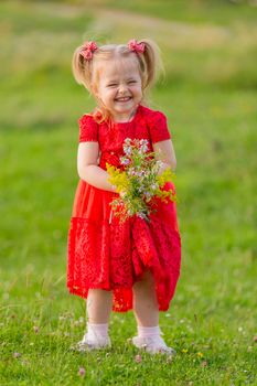 girl in a red dress and with a bouquet of wild flowers on the lawn