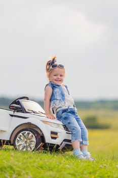 little girl standing near her baby car