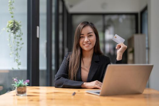 Young asian woman making laptop for mobile banking, purchasing online shopping with credit card
