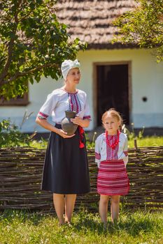 mother and daughter in Ukrainian national costumes near the fence