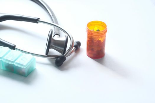 stethoscope and pills container on wooden background