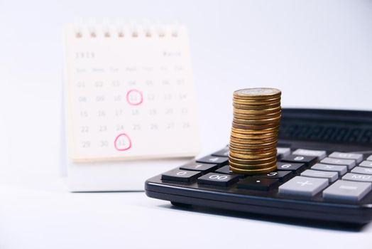 stack of coins and calendar on white background .