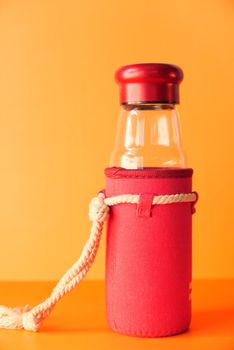 close up of empty glass bottle on orange background .
