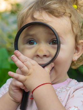 A child with a magnifying glass is studying the world. Selective focus. Kid.