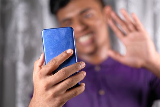 Smiling young man using his phone to make a video call.
