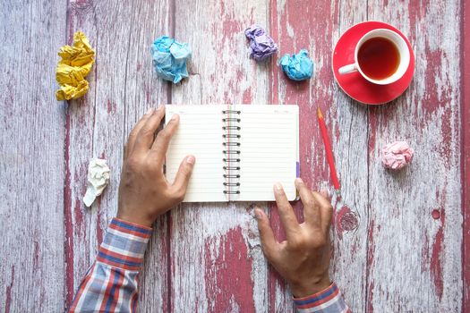 crumpled paper ball and notepad on wooden table