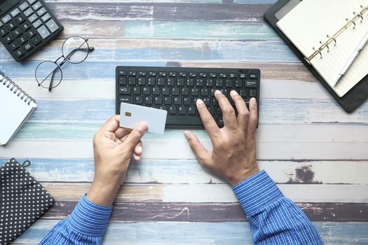 man hands holding credit card and using keyboard shopping online, top down