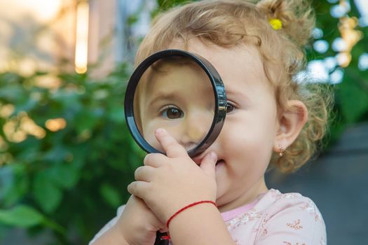 A child with a magnifying glass is studying the world. Selective focus. Kid.