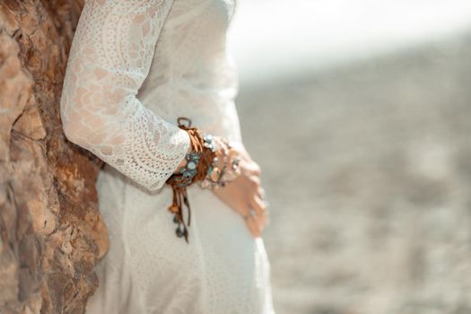 Middle aged woman looks good with blond hair, boho style in white long dress on the beach decorations on her neck and arms