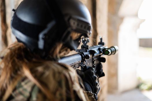 A woman in an army uniform shoots a firearm in an abandoned building