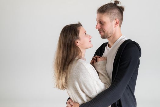 Portrait of a young caucasian couple of lovers hugging and looking at each other on a white background.