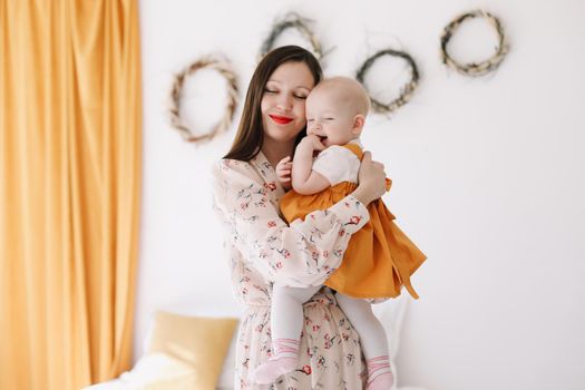 Photo of a happy mom holding and hugging little daughter, loving family sincere feelings.