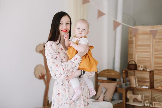 Photo of a happy mom holding and hugging little daughter, loving family sincere feelings.