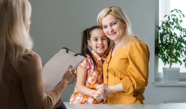 Hand of a professional family psychotherapist writing notes in front of a family with a child during a consultation.
